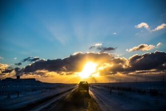 A car drives off into the sunset, much like gas-powered models are driving off into the sunset today. 